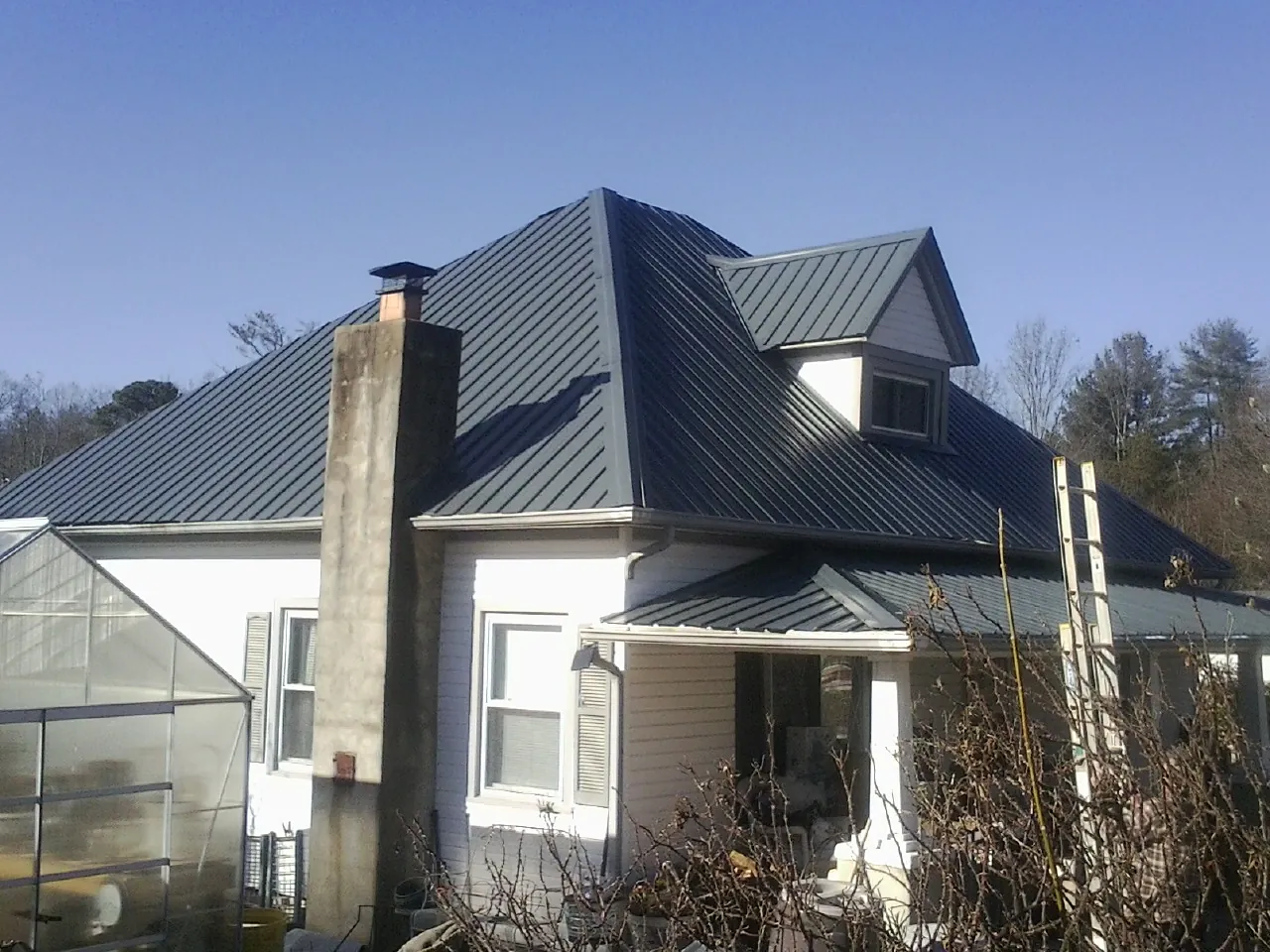 Dark blue standing seam metal roof on a white farmhouse with dormer — Slate & Tile Roof Repair by Roofing Brothers in Machipongo