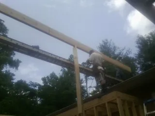 Carpenter setting a ridge beam over a new addition frame — Ice Dam Removal by Roofing Brothers in Machipongo