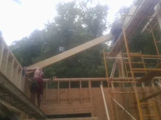 Carpenter raising a rafter beam on a new second story frame in Machipongo