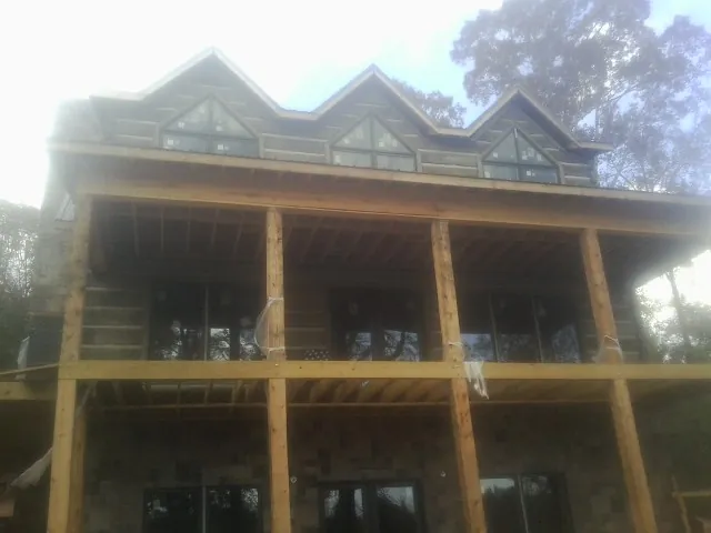Dormers and porch framing on a large log home under construction — Roof Coating work by our crew in Machipongo