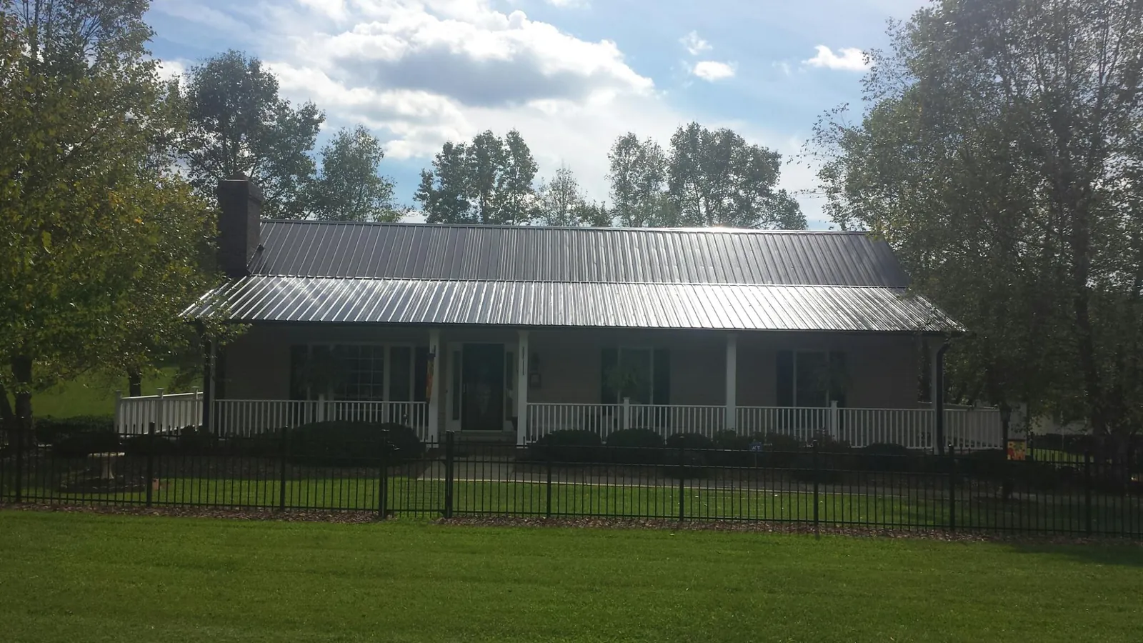 Gray metal roof on a brick ranch with a full width front porch — Gutter Guard Installation work by our crew in Machipongo