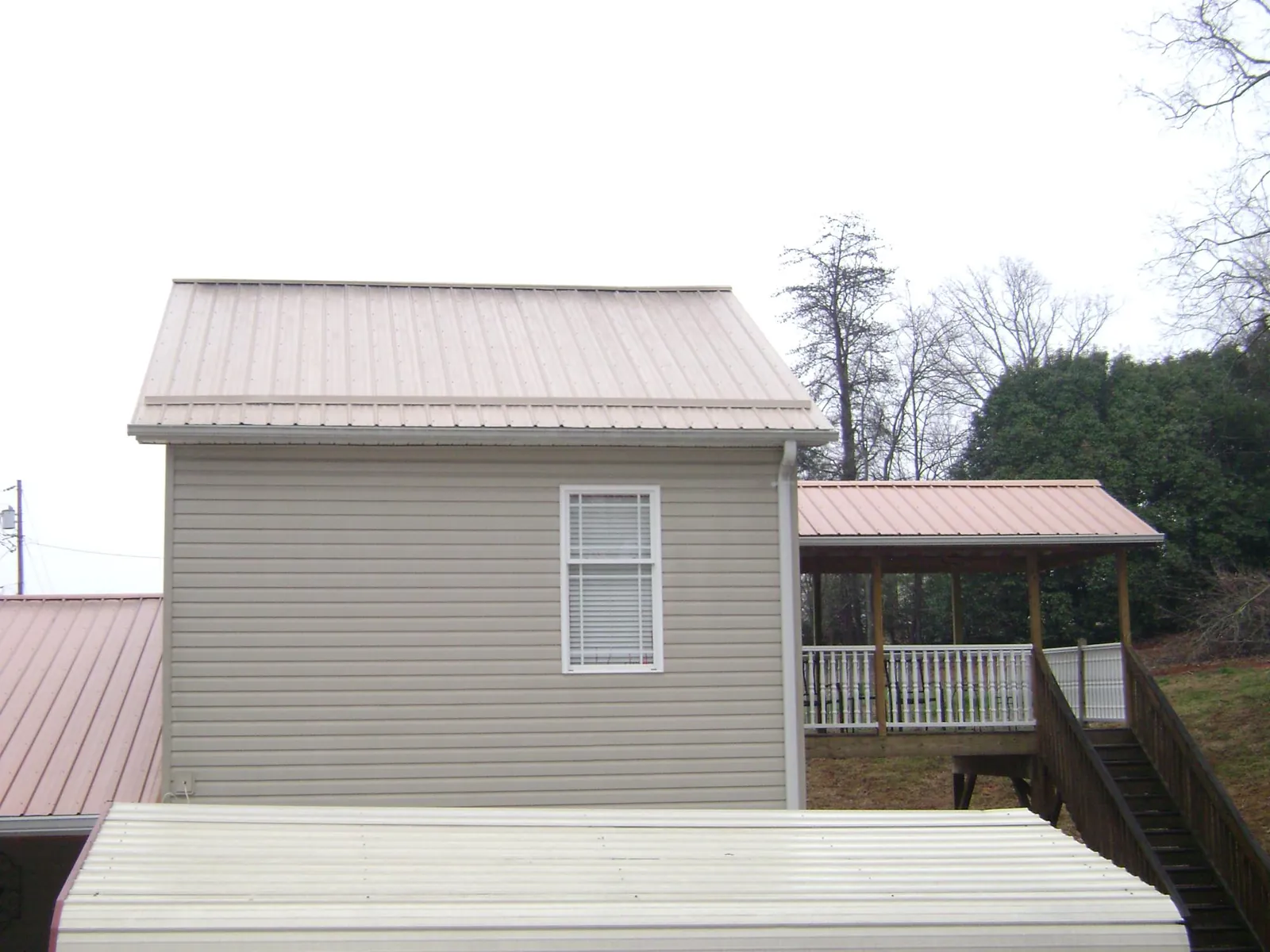 Tan metal roofs on a two story addition and attached porch, from a Roof Replacement job in Machipongo