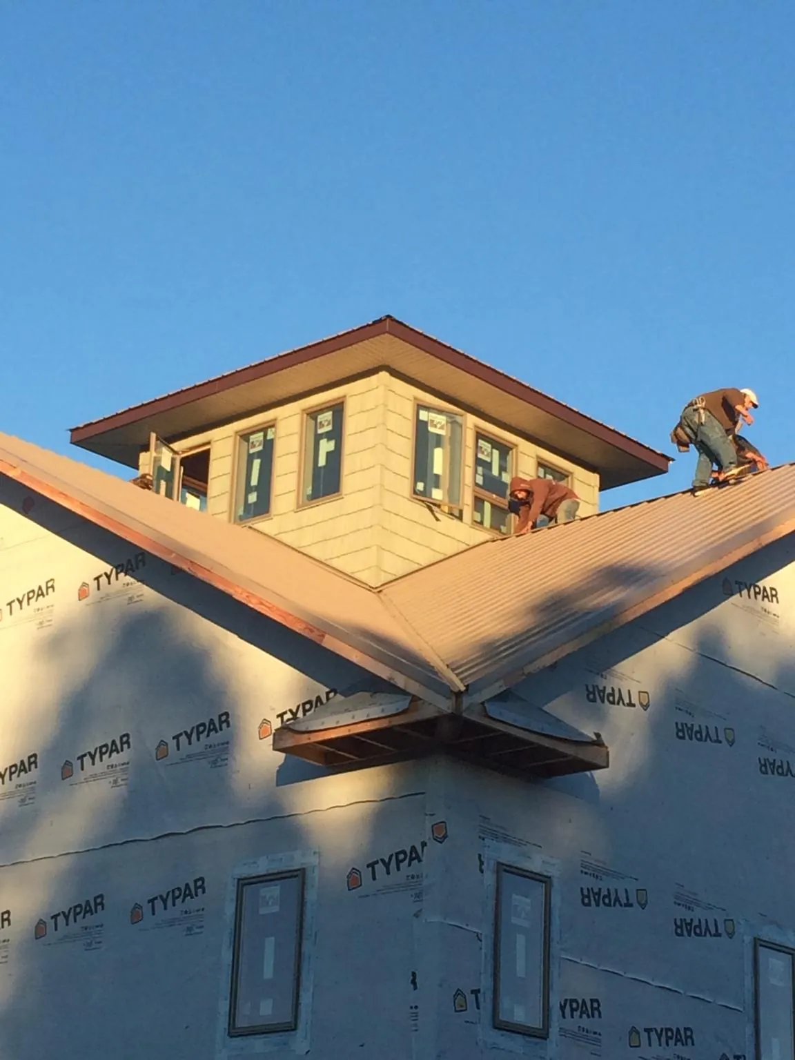 Roofers working around a rooftop cupola on a new metal roof at sunset — Roof Waterproofing in Machipongo by Roofing Brothers